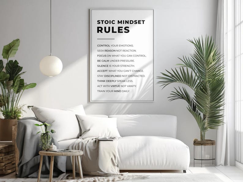 Może przedstawiać: Oprawiony wydruk z napisem "STOIC MINDSET RULES" wisi nad białą sofą. Na wydruku wymieniono zasady stoickiego nastawienia. Okrągła, biała lampa wisi u sufitu. Roślina doniczkowa znajduje się po lewej stronie sofy.