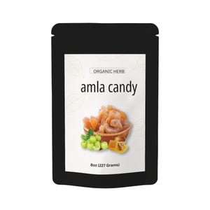 Könnte beinhalten: Ein schwarzer Beutel mit 227 Gramm Amla-Bonbons. Das Etikett zeigt den Text ORGANIC HERB und amla candy sowie eine Abbildung von getrockneten bernsteinfarbenen Fruchtstücken in einer Holzschale, grünen Amla-Beeren und etwas Honig.