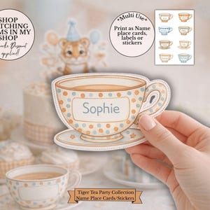 May include: A teacup-shaped sticker with the name "Sophie" on it, adorned with blue and orange polka dots. The image features a tiger illustration wearing a party hat and the text "Tiger Tea Party Collection Name Place Cards/Stickers."