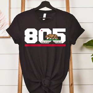May include: Black t-shirt featuring the number "805" in white block letters, with a red stripe and the words "CALIFORNIA REPUBLIC" below. A brown bear graphic is incorporated into the design, with a red star above the bear.