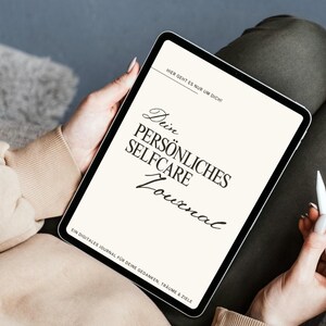Könnte beinhalten: Ein digitales Tablet zeigt ein Journal-Cover mit dem Text "Dein Persönliches Selfcare Journal" in schwarzer Schrift. Das Cover enthält auch die Sätze "Hier geht es nur um dich!" und "Ein digitales Journal für deine Gedanken, Träume & Ziele."