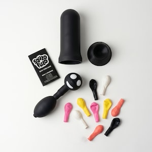 Könnte beinhalten: Ein schwarzer zylindrischer Behälter, ein schwarzer runder Sockel, eine schwarze Handpumpe mit weißem Smiley-Gesicht, eine schwarze Bedienungsanleitung mit der Aufschrift "SOUZO FUZO QUICK STARS GUIDE" und zehn kleine, nicht aufgeblasene Luftballons in Schwarz, Weiß, Gelb, Pink und Orange.