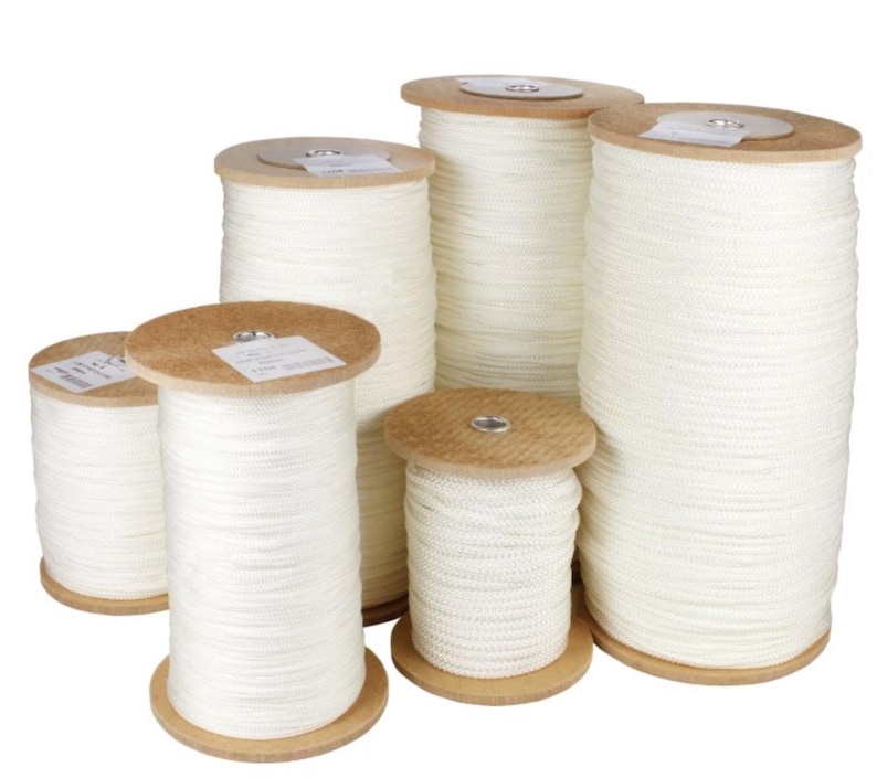 May include: Several spools of white rope are displayed, varying in size. The rope is tightly wound around wooden spools. The spools are arranged in a group, showcasing the different quantities of rope available. The rope appears to be a neutral white color.