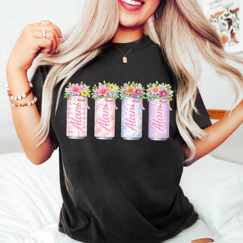 Pode incluir: Camiseta preta com quatro latas decorativas com arranjos florais. Cada lata tem um padr&atilde;o diferente e o nome "Alani" impresso. As latas s&atilde;o rosa, azul e roxo.