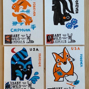 Puede incluir: Cuatro impresiones artísticas coloridas con ilustraciones estilizadas de una ardilla listada, un zorrillo, un mapache y un zorro. Cada impresión incluye el texto "USA Forever" y "Baby Wild Animals". La impresión de la ardilla listada tiene la palabra "Chipmunk".