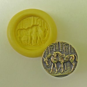May include: A gold-colored metal button with a raised design of two horses standing side-by-side. The horses are in a detailed, stylized design with a saddle on one of the horses. The button is surrounded by a decorative border.