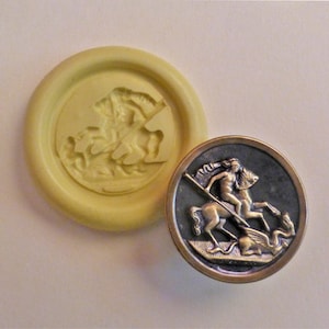 May include: A gold-colored metal button with a raised image of a knight on horseback slaying a dragon. The button is round and has a dark gray background.