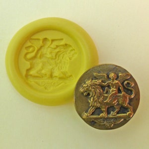 May include: A gold-colored metal button with a raised design of a winged figure riding a lion. The button is round and has a detailed design.