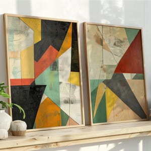 Può includere: Due stampe artistiche astratte incorniciate. L'opera presenta forme geometriche in nero, giallo, arancione, rosso e verde acqua. Le cornici sono di colore legno chiaro. Le stampe sono esposte su una mensola di legno con piante e libri.