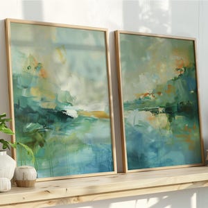 Puede incluir: Dos impresiones artísticas abstractas enmarcadas con un tema de paisaje. La obra de arte presenta una mezcla de tonos turquesa, verdes y dorados. Los marcos son de madera clara. Las impresiones se exhiben en una estantería de madera con plantas y libros.