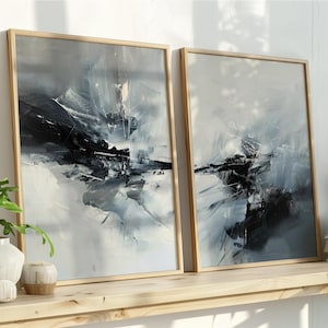 Peut inclure: Deux impressions d'art abstraites encadrées, avec une palette de couleurs neutres de blanc, gris et noir. L'œuvre est exposée sur une étagère en bois clair avec des plantes décoratives et des livres. Les cadres sont en bois clair.