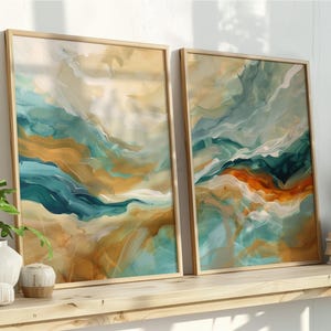 May include: Two framed abstract art prints with a light wood frame. The artwork features flowing brushstrokes in shades of teal, orange, and beige. The prints are displayed on a wooden shelf with decorative items and plants.