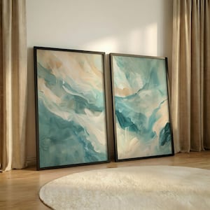 May include: Two rectangular framed wall art pieces featuring abstract fluid brushstrokes in shades of teal, turquoise, white, and soft beige. The paintings are encased in thin black frames and display a layered, blended composition of colors.