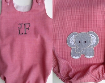 May include: A red and white gingham baby romper with a gray elephant applique on the lower right. The romper has a rounded neckline, button closures on the shoulders, and an embroidered monogram on the chest.
