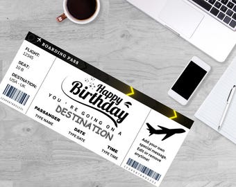 May include: A black and white boarding pass with the text "Happy Birthday, You're Going on a Destination". The pass includes a flight number, seat, and destination. A coffee cup, laptop, phone, and notepad are also visible.