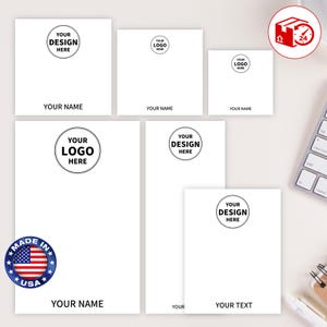 May include: A collection of white stationery items with customizable text and logos. The designs include various sizes of notepads and cards, with the text "YOUR NAME", "YOUR LOGO HERE", and "YOUR DESIGN HERE". A "Made in USA" sticker is visible.