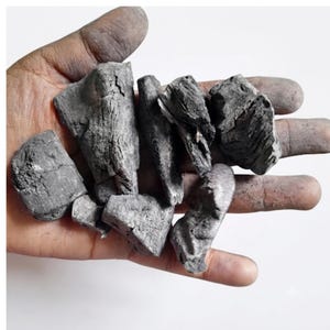 Puede incluir: Varios trozos irregulares y dentados de carbón con un acabado mate en gris oscuro y negro. La superficie de cada pieza muestra grietas naturales profundas y una textura rugosa y porosa característica.