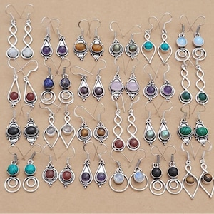 Puede incluir: Una colección de pendientes plateados con diversos acentos de piedras preciosas. Los pendientes presentan una variedad de formas y diseños, incluyendo gotas, espirales y engastes circulares. Las piedras preciosas incluyen turquesa, amatista y ojo de tigre.