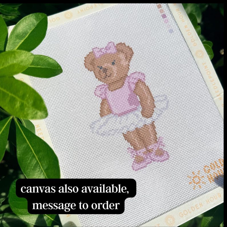 Puede incluir: Un lienzo de punto de aguja con un oso de peluche marr&oacute;n que lleva un maillot rosa claro, un tut&uacute; blanco, un lazo rosa a juego y zapatillas de ballet rosas. El borde del lienzo incluye el texto GOLDEN HOUR NEEDLEPOINT en un patr&oacute;n.