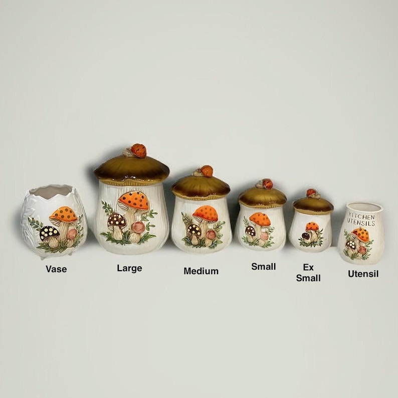 K&ouml;nnte beinhalten: Ein Set aus sechs Keramikbeh&auml;ltern f&uuml;r die K&uuml;che mit Pilzmotiven. Es besteht aus einer Vase, vier Vorratsdosen mit braunen Deckeln, beschriftet als Large, Medium, Small und Ex Small, sowie einem Utensilienhalter mit der Aufschrift Kitchen Utensils.