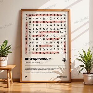 May include: A framed print with the word "entrepreneur" in large, bold letters. The print features a word search puzzle with words related to business and innovation. The print is displayed on a wooden floor with two potted plants.