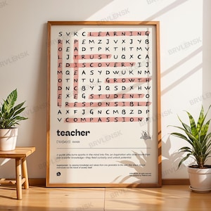 Puede incluir: Un póster enmarcado con un marco de madera que presenta un rompecabezas de búsqueda de palabras con la palabra "teacher" en la parte inferior. El rompecabezas tiene palabras como "learning" y "discovery" resaltadas en rosa. Un pequeño taburete de madera y plantas en macetas están en primer plano.