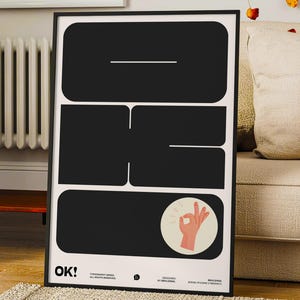 May include: A rectangular framed poster featuring large black geometric shapes on a white background. The design includes a stylised hand making an okay gesture within a circle and the text OK! in the bottom left corner with additional small text.
