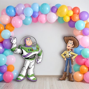May include: A colorful balloon arch frames cutouts of Buzz Lightyear and Woody from Toy Story. The balloons are in shades of pink, blue, orange, yellow, and purple. Buzz Lightyear is in his signature space suit, and Woody is in a cowboy outfit.