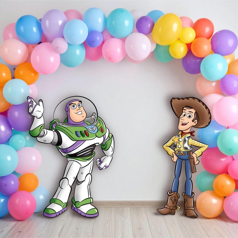 May include: A colorful balloon arch frames cutouts of Buzz Lightyear and Woody from Toy Story. The balloons are in shades of pink, blue, orange, yellow, and purple. Buzz Lightyear is in his signature space suit, and Woody is in a cowboy outfit.