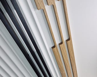 Puede incluir: Toma en ángulo de un diseño arquitectónico moderno con elementos lineales blancos y negros. Tres piezas de madera en forma de asa están colocadas en diagonal, añadiendo un contraste natural a las líneas geométricas. El diseño sugiere un tema de decoración interior contemporáneo.