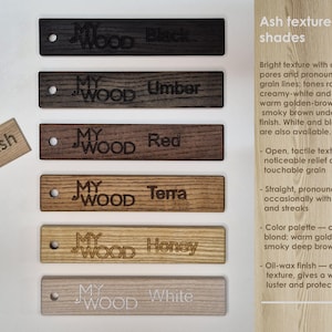 May include: Wooden samples in various shades, including black, umber, red, terra, honey, and white. Each sample is rectangular with a hole and the text "MY WOOD". The image also includes a small "Ash" sample.