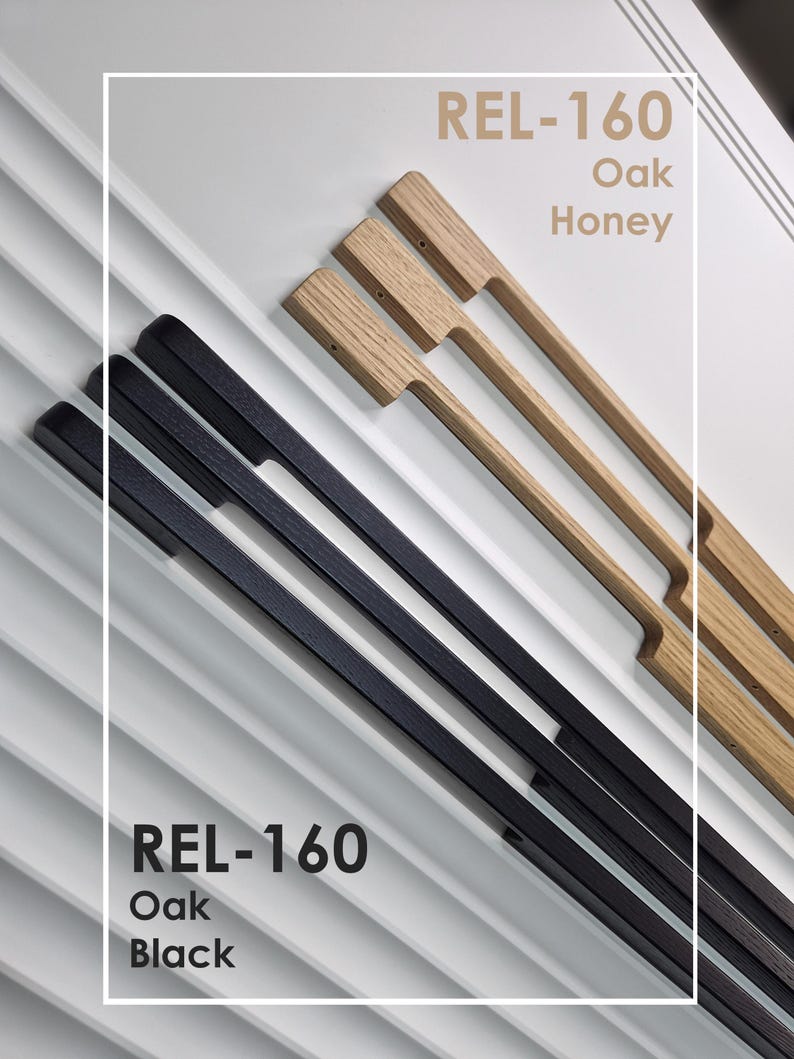 May include: An overhead shot of cabinet pulls in two colors, black and oak honey. The pulls are rectangular with a handle. The text "REL-160 Oak Black" and "REL-160 Oak Honey" is displayed in the image.