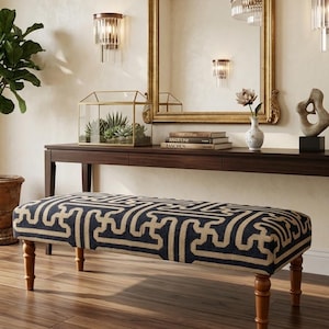 May include: A rectangular upholstered bench featuring a dark navy blue and beige geometric maze pattern. The bench is supported by four turned wooden legs in a medium brown finish, providing a stable base for this piece of furniture.