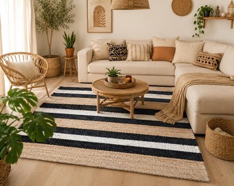 May include: A rectangular area rug featuring horizontal stripes in alternating bands of natural tan jute, solid black, and crisp white. The rug is woven with a textured, organic fiber construction, providing a flat surface that spans the floor area.