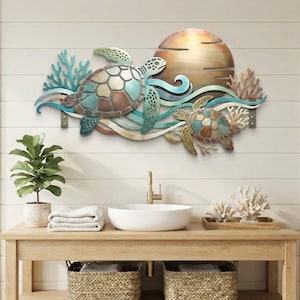 May include: A metal wall art piece featuring two sea turtles swimming among coral and waves, set against a large circular sun. The design incorporates shades of teal, copper, and bronze, creating a layered, dimensional ocean-themed scene.