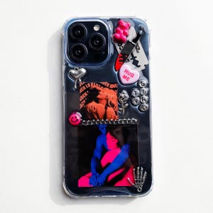 Könnte beinhalten: Transparente Handyhülle mit dunklem Hintergrund, verziert mit verschiedenen Charms. Enthält einen rosa Gummibären, ein Messer, ein Herz mit "HUG ME" und eine Grafik von zwei sich umarmenden Figuren. Weitere Charms: Smiley und Skeletthand.
