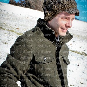 May include: A man wearing a brown and gray knitted hat with ear flaps and a green jacket. The hat has a unique textured design and the jacket has multiple pockets.
