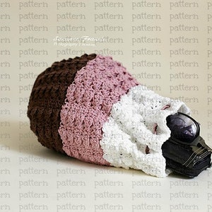 May include: A crocheted bag with three sections in brown, pink, and white. The bag is lying on a white surface and has a black object inside.