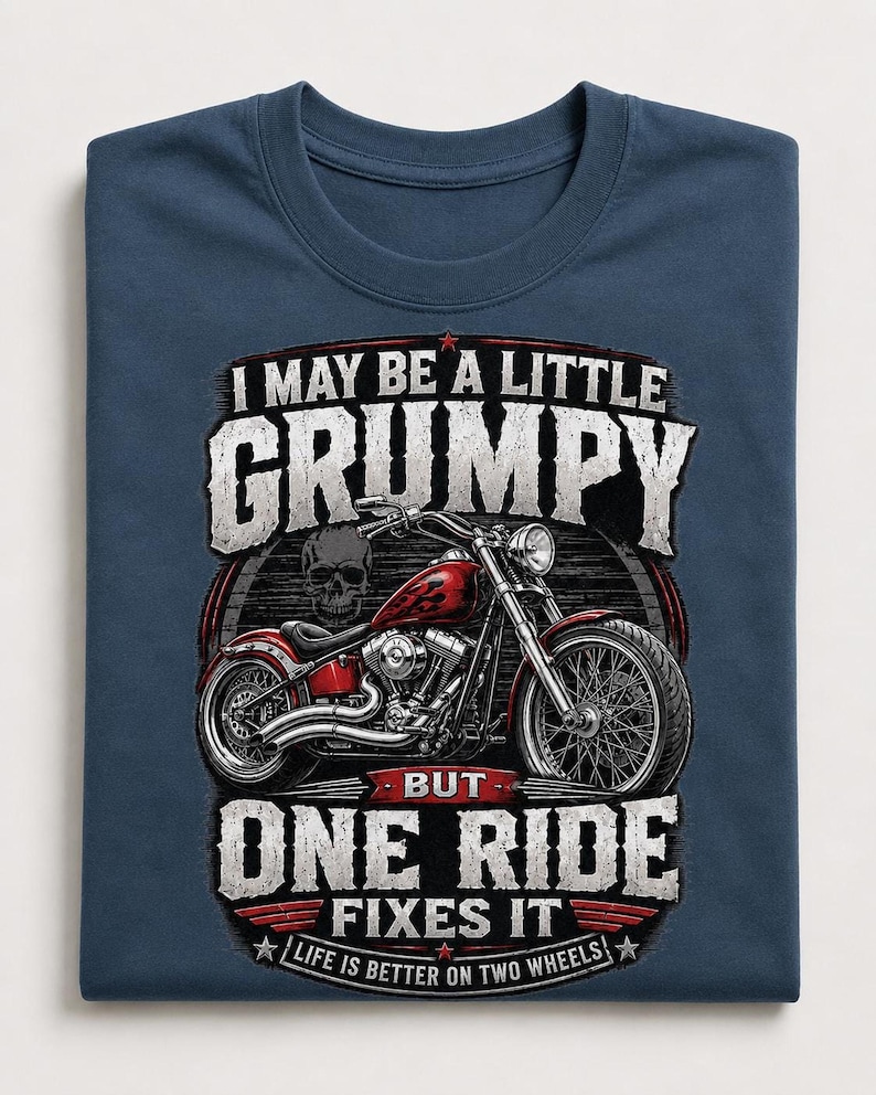 A folded navy blue t-shirt displays a red motorcycle graphic and the text "I MAY BE A LITTLE GRUMPY BUT ONE RIDE FIXES IT LIFE IS BETTER ON TWO WHEELS."
