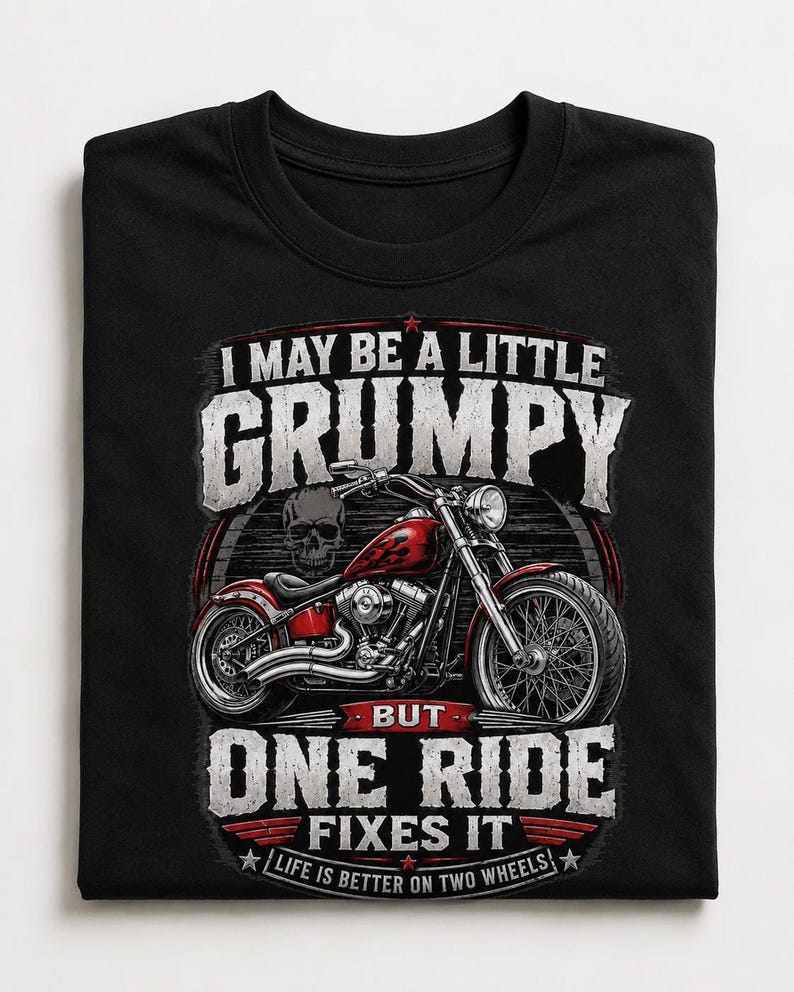 A folded black t-shirt displays a red motorcycle graphic and the text "I MAY BE A LITTLE GRUMPY BUT ONE RIDE FIXES IT LIFE IS BETTER ON TWO WHEELS."
