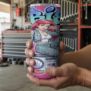 Pu&ograve; includere: Un bicchiere cilindrico con una vivace stampa grafica di un personaggio dai capelli rossi che indossa una giacca a motivi e un top bianco. Il design include scritte in stile graffiti, un motivo a conchiglia e un lettore di cassette con il testo MIKOS.