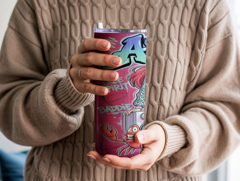 Pu&ograve; includere: Un bicchiere cilindrico in acciaio inossidabile con un vivace design in stile graffiti, caratterizzato da una grande lettera A, le scritte Free Spirit e Baddie e un'illustrazione di un granchio in tonalit&agrave; rosso, rosa e blu con coperchio.