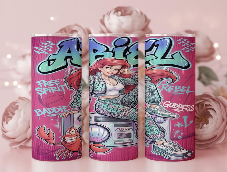 Pu&ograve; includere: Un bicchiere cilindrico con sfondo rosa caratterizzato da un'illustrazione in stile graffiti di un personaggio dai capelli rossi, che indossa giacca e pantaloni a fantasia, seduto su un boombox. Il testo include "FREE SPIRIT", "BADDIE", "REBEL" e "GODDESS".