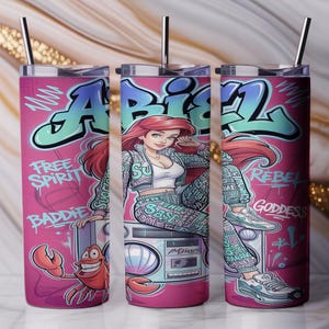 Pu&ograve; includere: Un bicchiere cilindrico in acciaio inossidabile con un design graffiti rosa che raffigura un personaggio dai capelli rossi seduto su un boombox, un granchio e il testo "ABIEL", "FREE SPIRIT", "BADDIE", "REBEL" e "GODDESS". Include coperchio e cannuccia in metallo.
