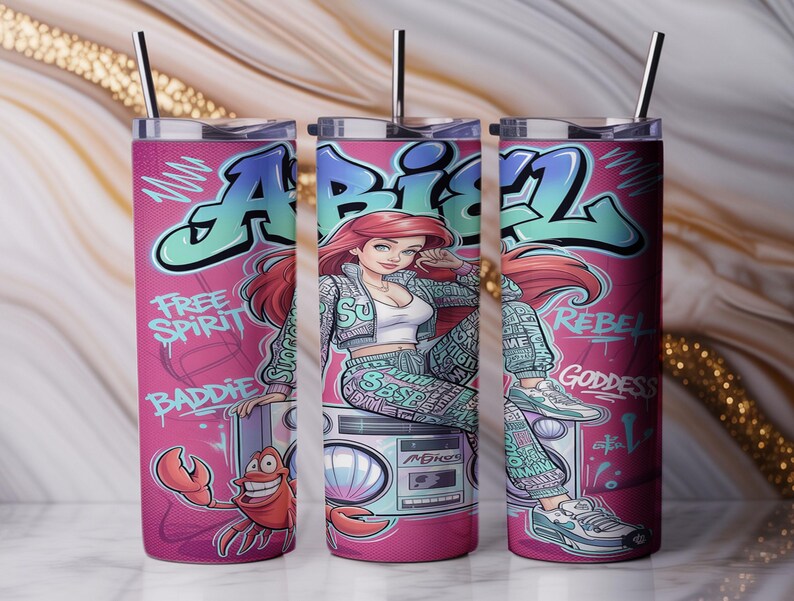 Pu&ograve; includere: Un bicchiere cilindrico in acciaio inossidabile con un design graffiti rosa che raffigura un personaggio dai capelli rossi seduto su un boombox, un granchio e il testo "ABIEL", "FREE SPIRIT", "BADDIE", "REBEL" e "GODDESS". Include coperchio e cannuccia in metallo.