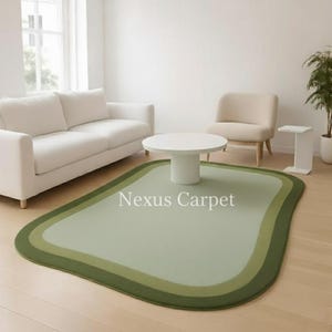 May include: A green area rug with a unique, rounded rectangular shape. The rug features three shades of green, with a darker green border and lighter green center. The text "Nexus Carpet" is printed on the rug.
