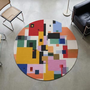 Può includere: Un tappeto rotondo con un colorato design geometrico. Il tappeto presenta quadrati e rettangoli rossi, gialli, verdi, blu, rosa e neri. Una poltrona in pelle nera e una sedia con schienale intrecciato sono visibili.