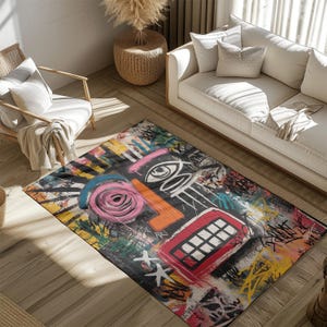 May include: A rectangular area rug with a colorful abstract face design. The rug features a black background with a large pink rose, orange nose, and red mouth. The design includes graffiti-style elements.