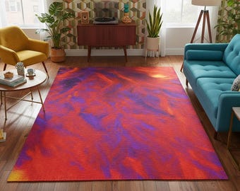 May include: A rectangular area rug with a vibrant abstract design in shades of red, purple, and yellow. The rug is placed on a hardwood floor in a living room setting, with furniture and plants visible in the background.