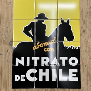 Può includere: Un set di nove piastrelle quadrate con una silhouette nera di un cavaliere a cavallo su sfondo giallo. Le piastrelle mostrano le parole "abonado con NITRATO DE CHILE" in bianco e oro.
